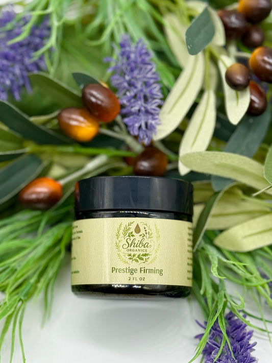 Jar of Shiba prestige firming cream surrounded by green leaves and purple flowers on a white background